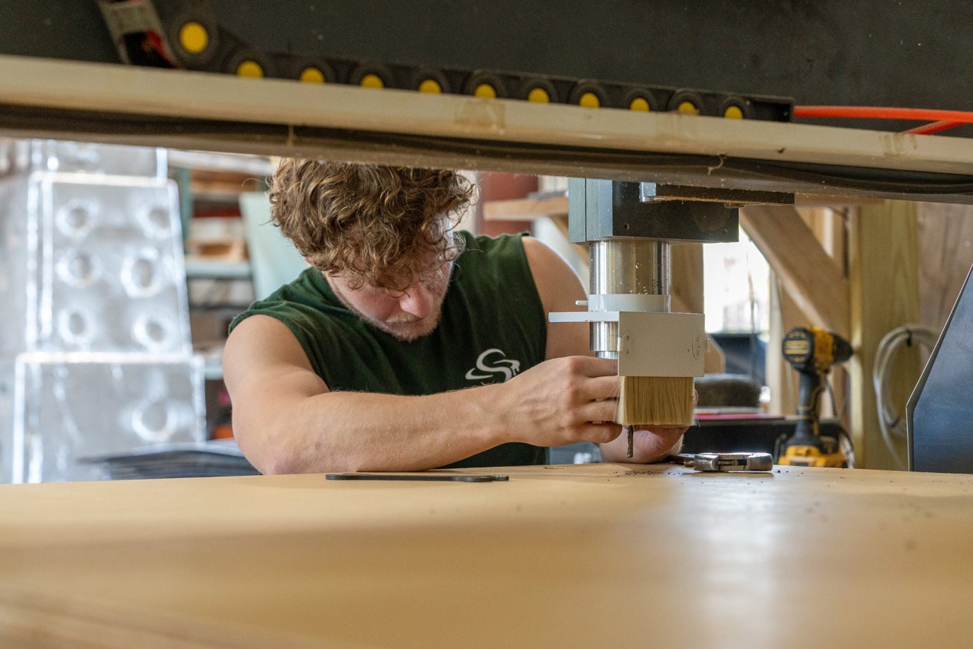 A fabricator setting up the CNC router spindle over a sheet of wood