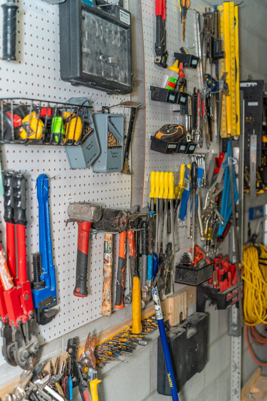 Pegboard wall full of hammers, wrenches, drill bits, levels and screwdrivers