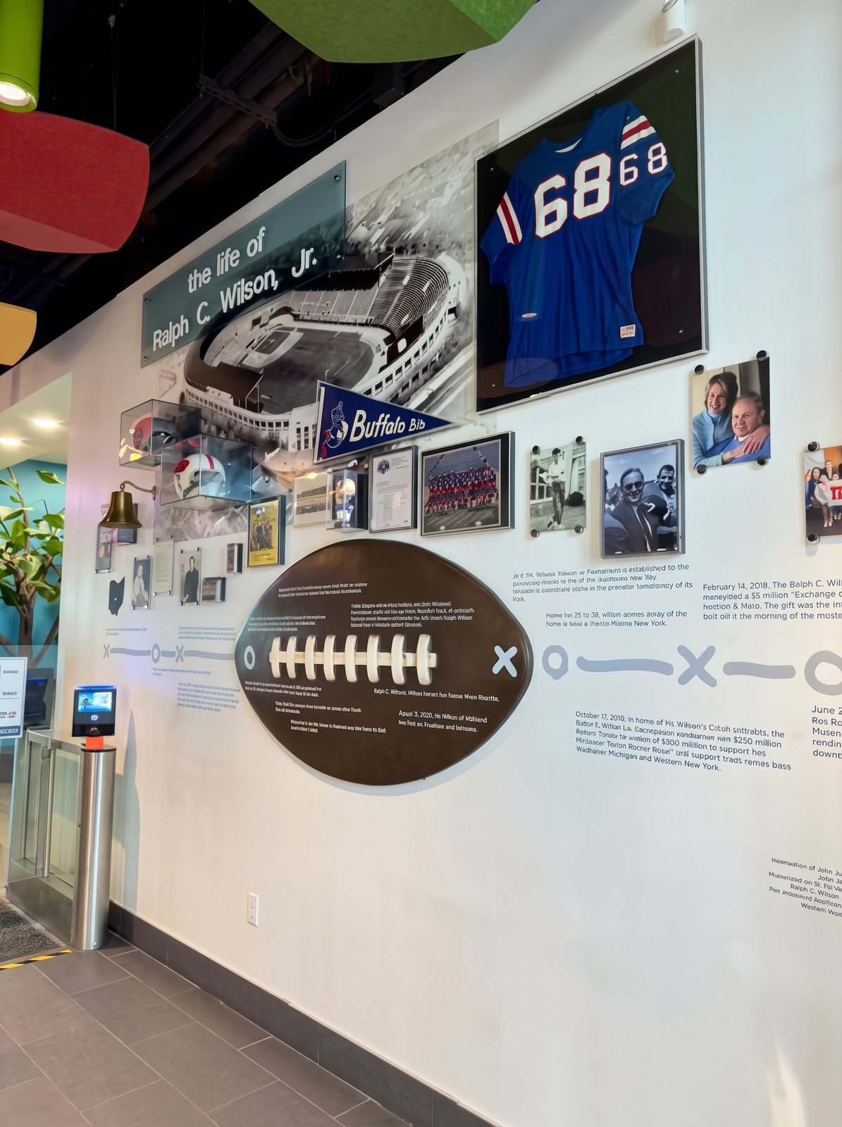 A football hall-of-fame display wall with a framed jersey, photos and a large football graphic