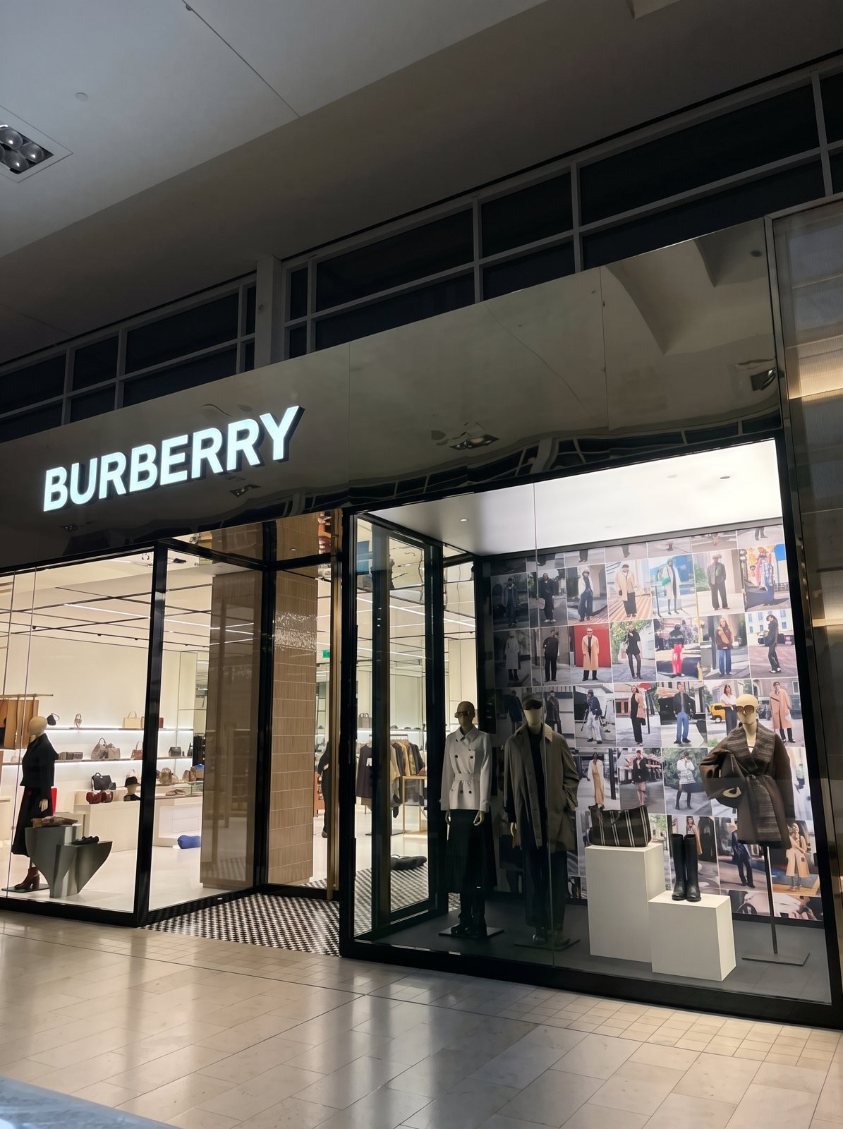 A Burberry storefront at night with a full window display of mannequins