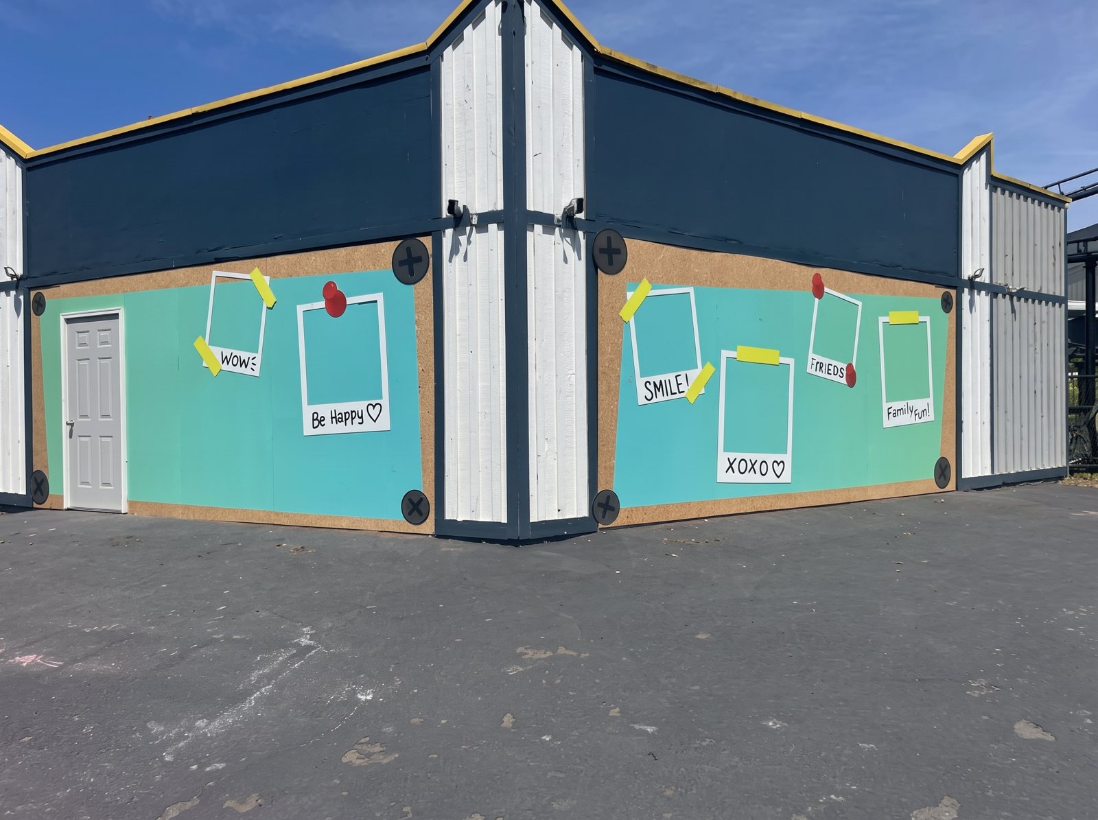 A store exterior wrapped in teal graphics with photo frames and painted doors