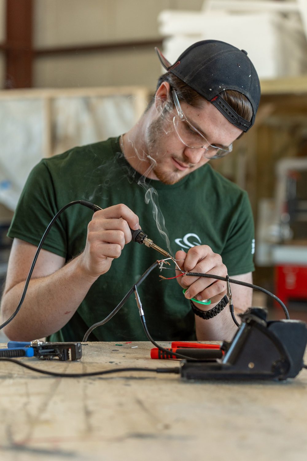 A technician in safety glasses soldering wires
